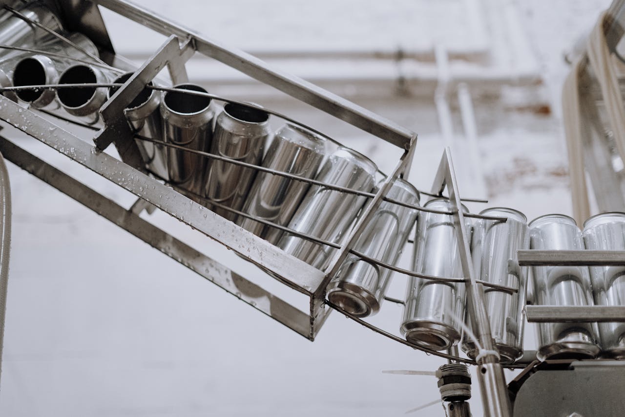Conveyor belt with empty aluminum cans in a factory setting, showcasing production equipment.